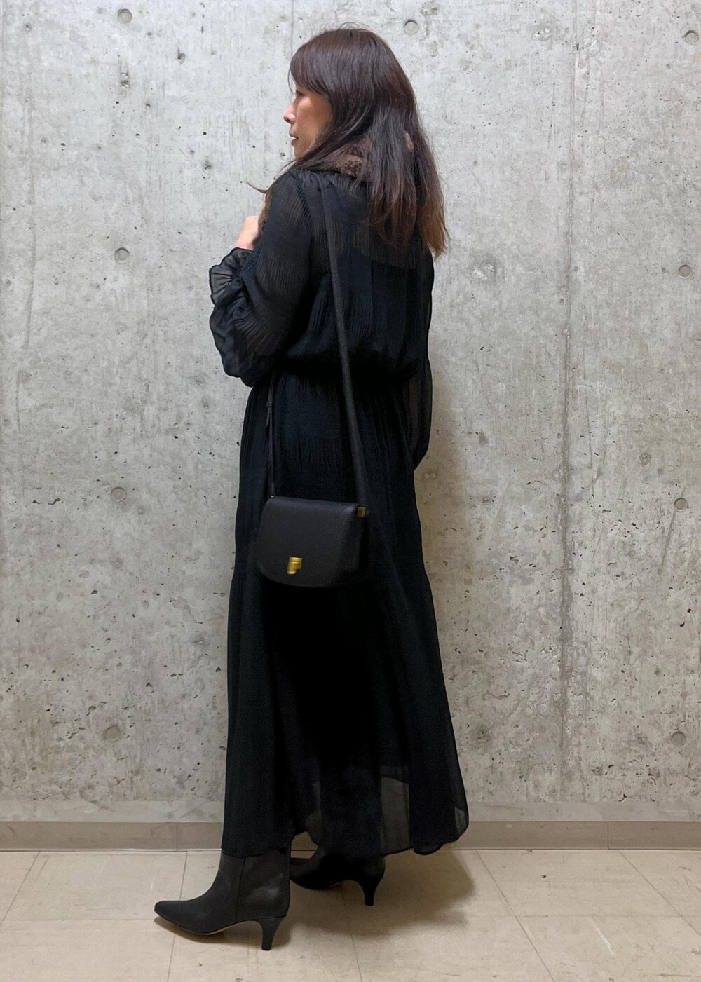 ブラック系のショルダーバッグ、ブラック系のブーツ、ブラック系のワンピースを着用したレディースの冬コーディネートの3枚目の写真