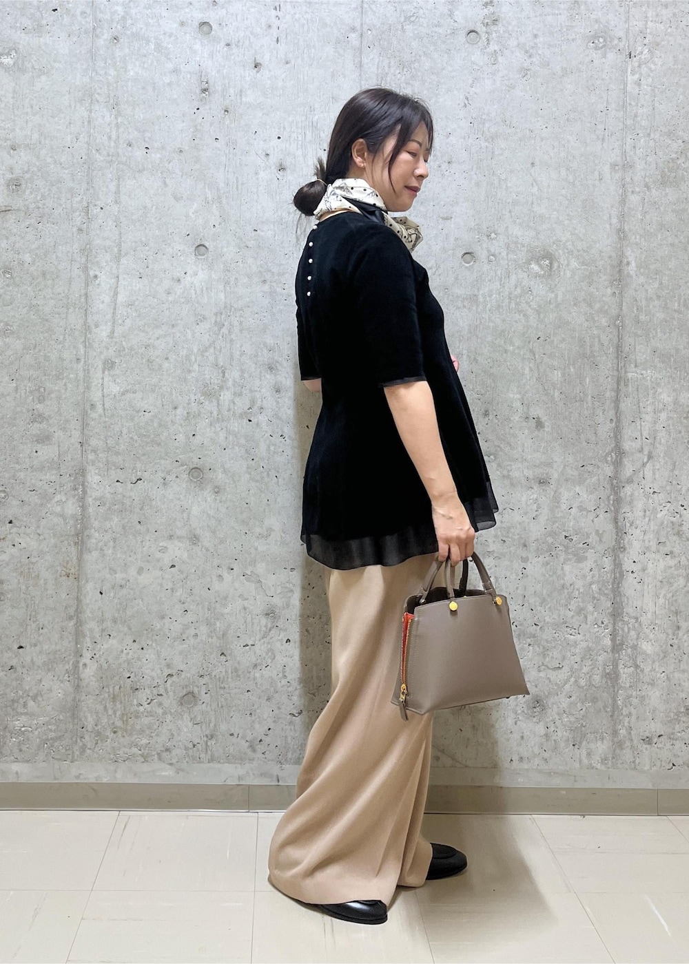 ブラウン系のハンドバッグ、ベージュ系のその他パンツ、ブラック系のローファーを着用したレディースの秋コーディネートの2枚目の写真