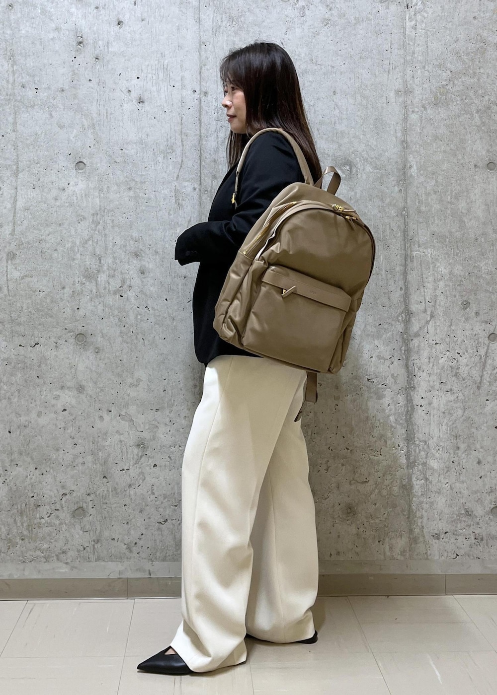 ブラック系のパンプス、ベージュ系のバックパック/リュック、ベージュ系のその他パンツを着用したレディースの冬コーディネートの2枚目の写真