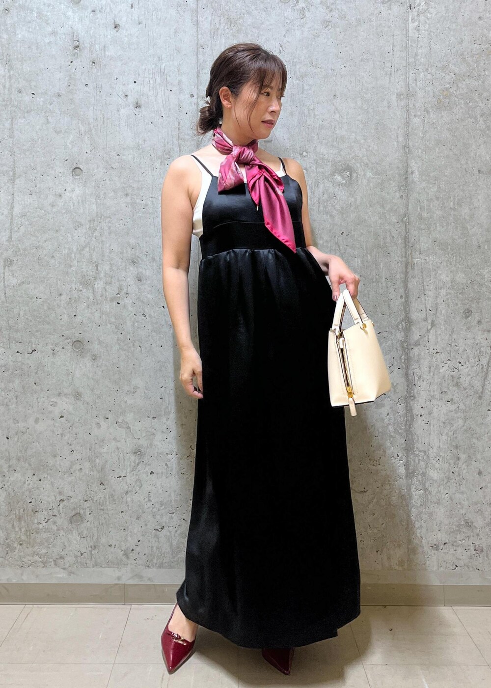 ホワイト系のキャミソール、ベージュ系のハンドバッグ、レッド系のパンプスを着用したレディースの夏コーディネートの4枚目の写真