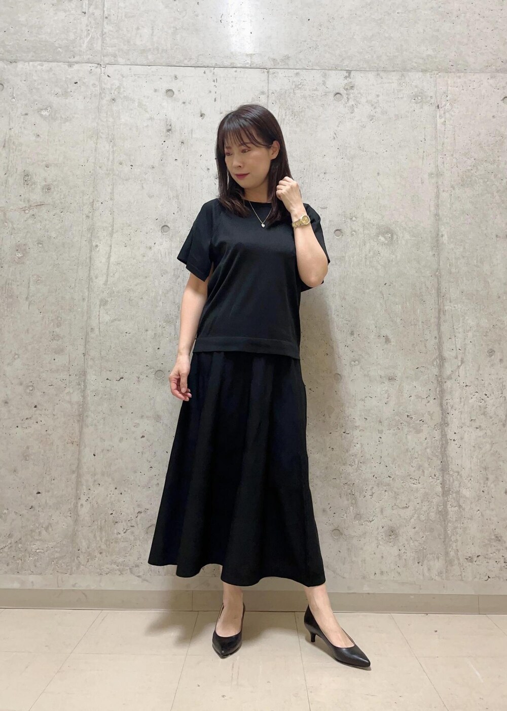 ブラック系のニット/セーター、ホワイト系のハンドバッグ、ブラック系のスカートを着用したレディースの夏コーディネートの2枚目の写真