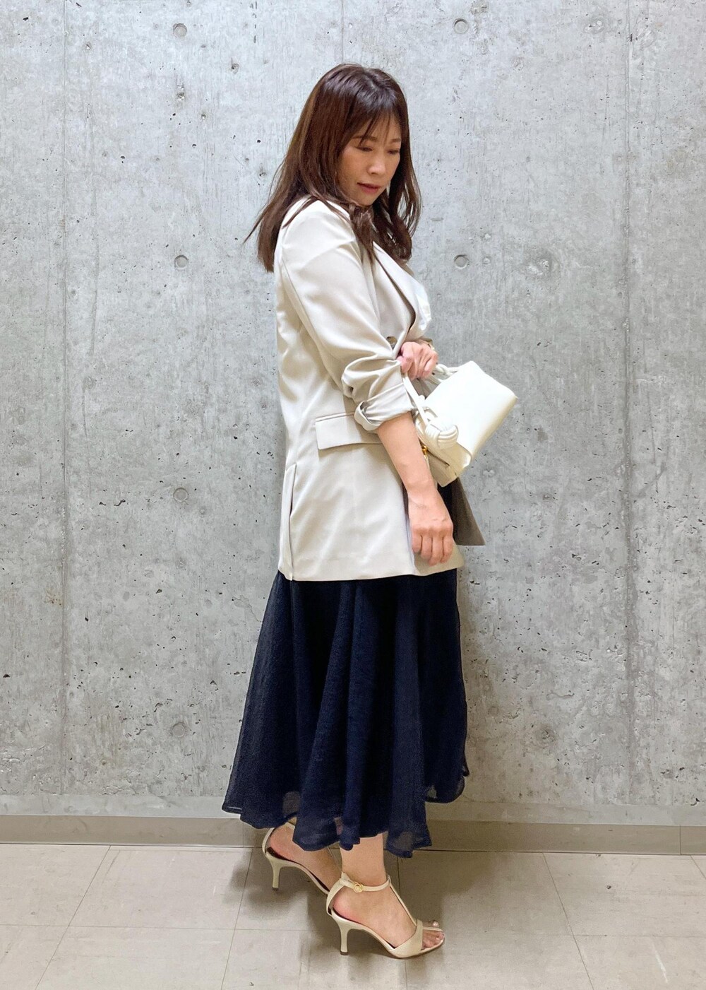 ブルー系のスカート、ホワイト系のサンダル、ホワイト系のショルダーバッグを着用したレディースの夏コーディネートの2枚目の写真