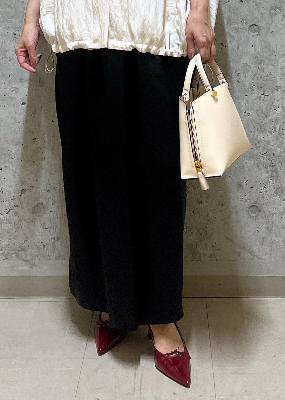 ホワイト系のキャミソール、ベージュ系のハンドバッグ、レッド系のパンプスを着用したレディースの夏コーディネートの6枚目の写真