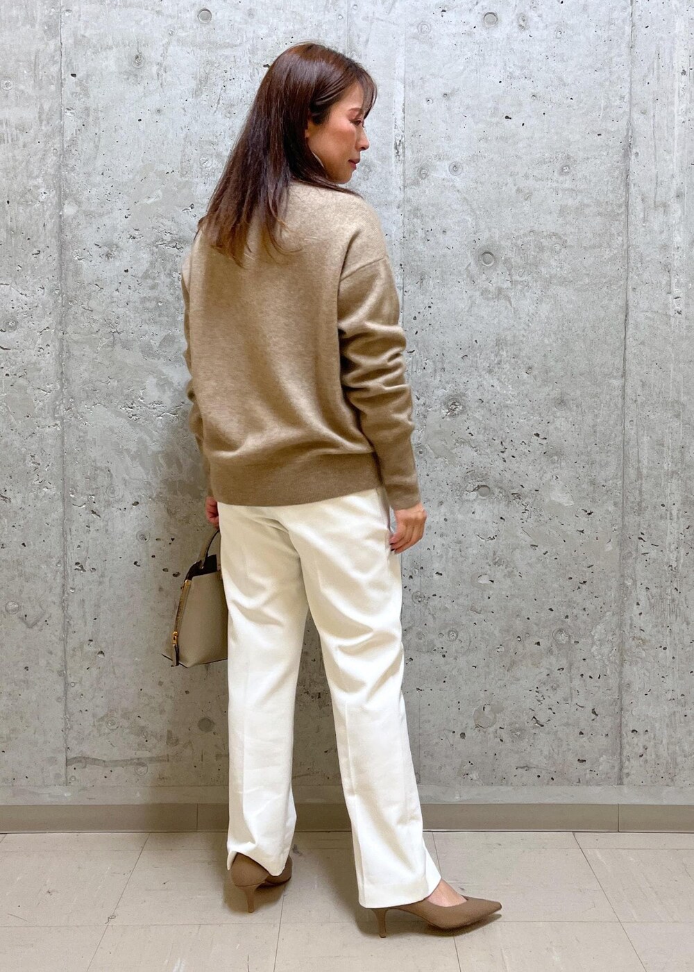 ベージュ系のパンプス、ベージュ系のハンドバッグ、ホワイト系のその他パンツを着用したレディースの冬コーディネートの3枚目の写真