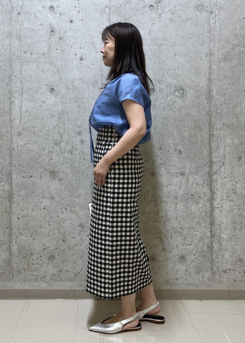 シルバー系のパンプス、ホワイト系のハンドバッグ、ブラック系のスカートを着用したレディースの夏コーディネートの2枚目の写真