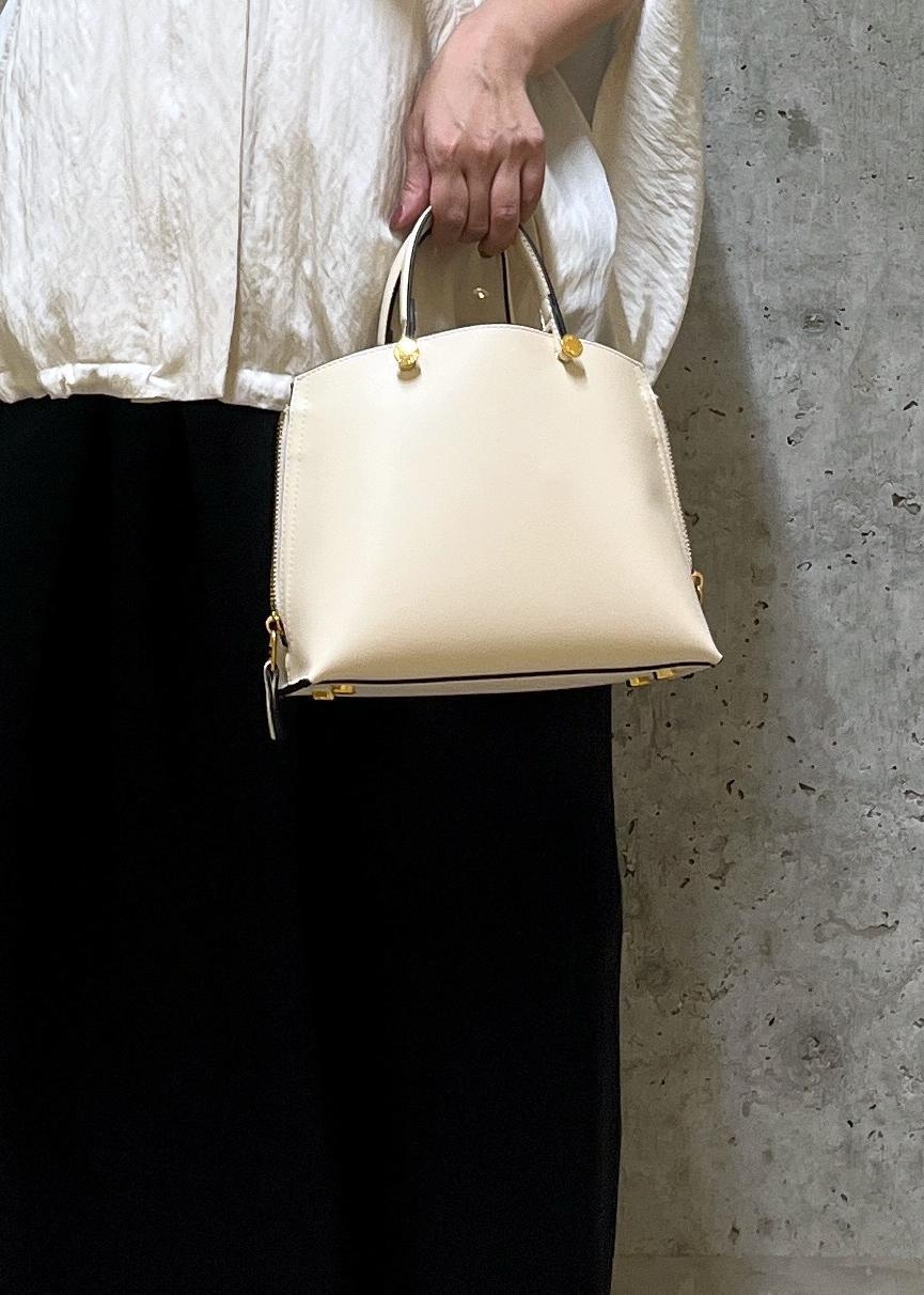 ホワイト系のキャミソール、ベージュ系のハンドバッグ、レッド系のパンプスを着用したレディースの夏コーディネートの7枚目の写真