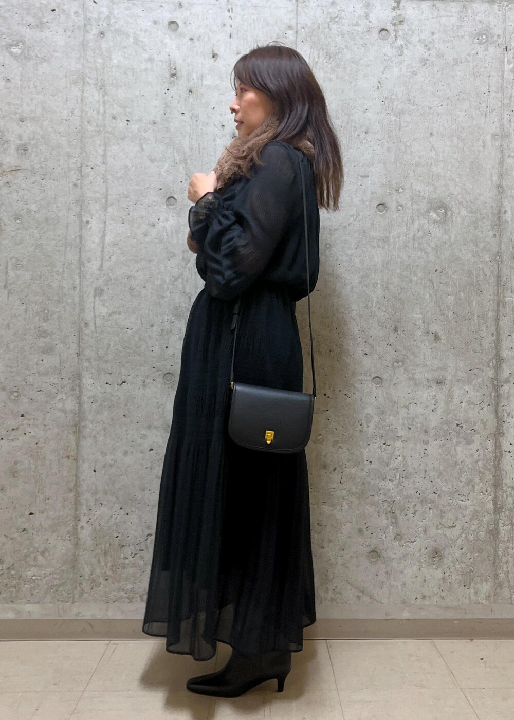 ブラック系のショルダーバッグ、ブラック系のブーツ、ブラック系のワンピースを着用したレディースの冬コーディネートの2枚目の写真