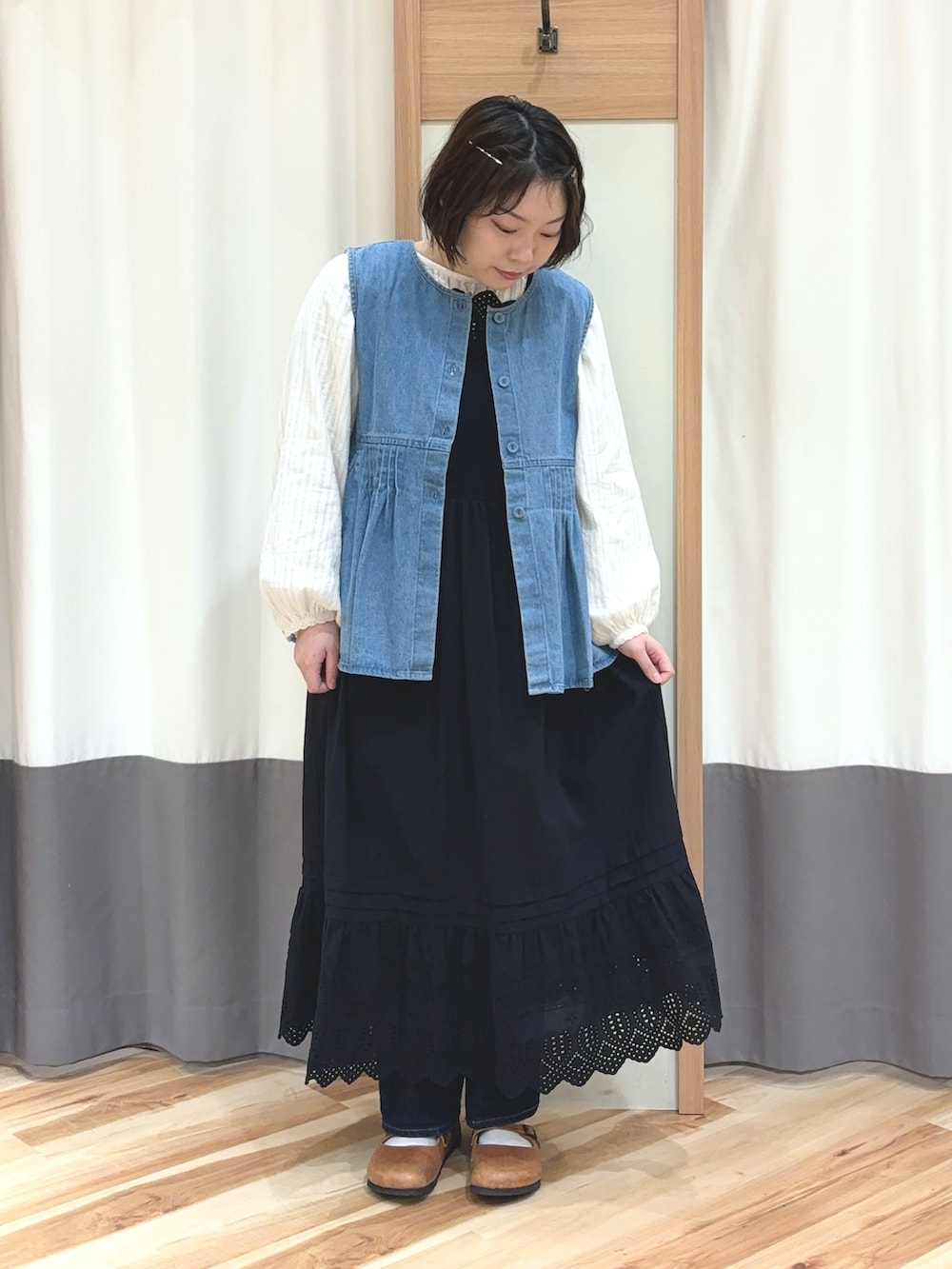 ホワイト系のシャツ/ブラウス、ブルー系のベスト、ブラック系のワンピースを着用したレディースの春コーディネートの2枚目の写真