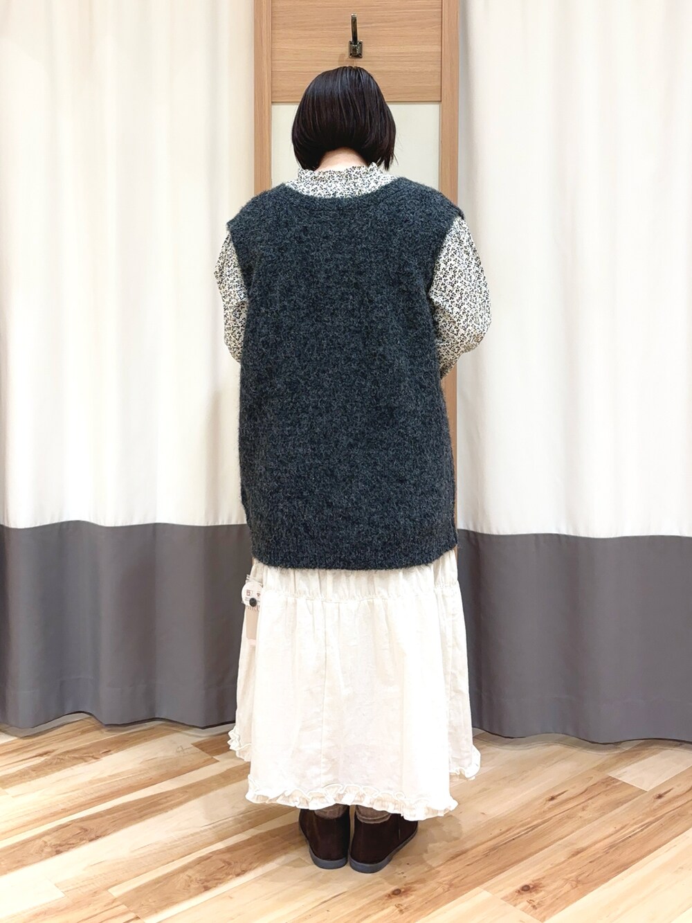 グレー系のカーディガン/ボレロ、グレー系のベスト、ホワイト系のスカートを着用したレディースの冬コーディネートの2枚目の写真