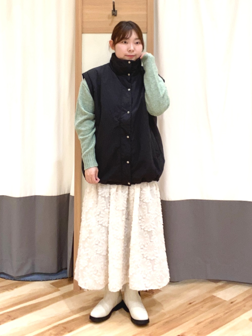 グリーン系のニット/セーター、ブラック系のノーカラージャケット、ホワイト系のスカートを着用したレディースの冬コーディネートの2枚目の写真