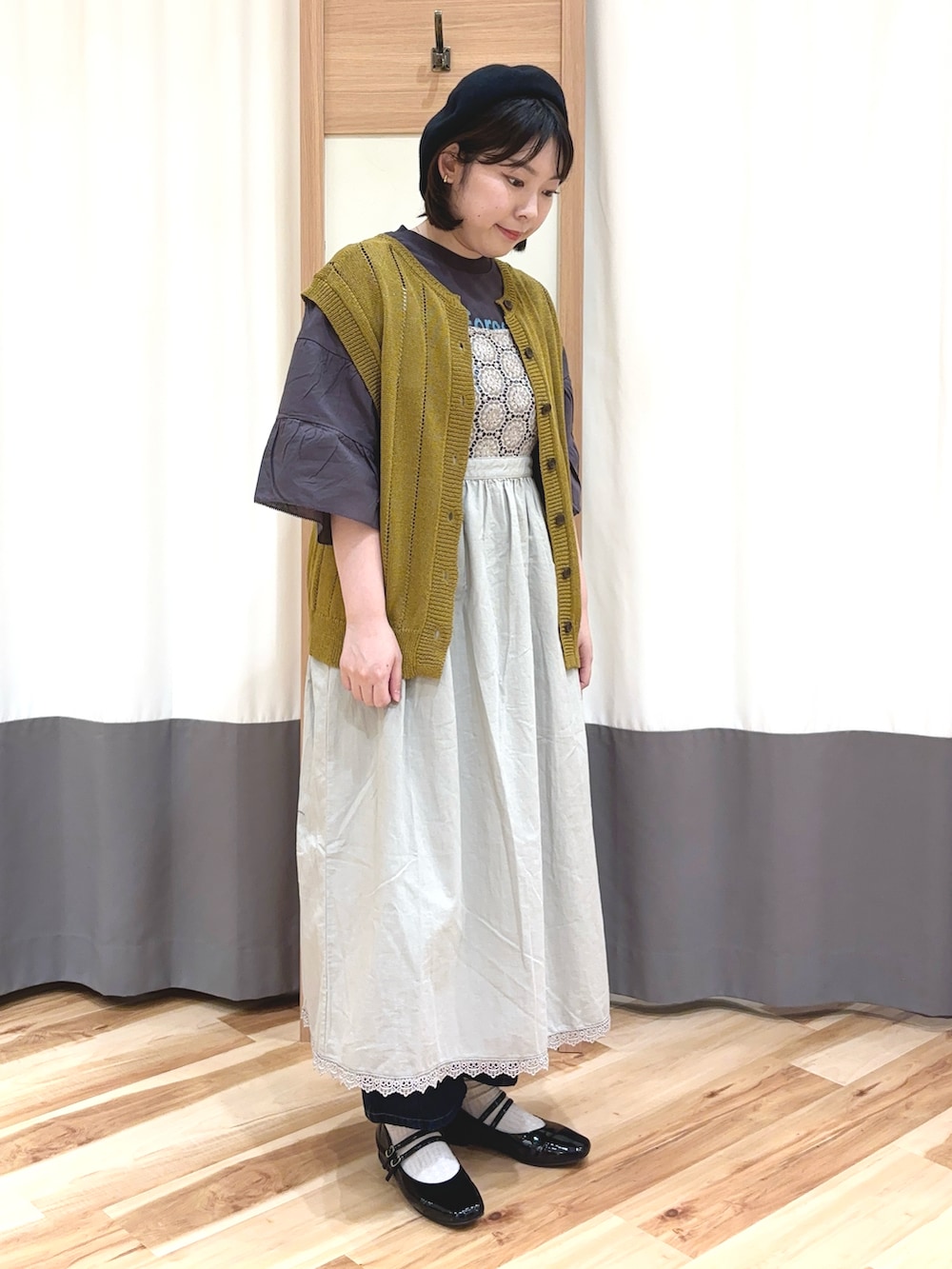 グレー系のTシャツ/カットソー、イエロー系のベスト、ベージュ系のワンピースを着用したレディースの夏コーディネートの2枚目の写真