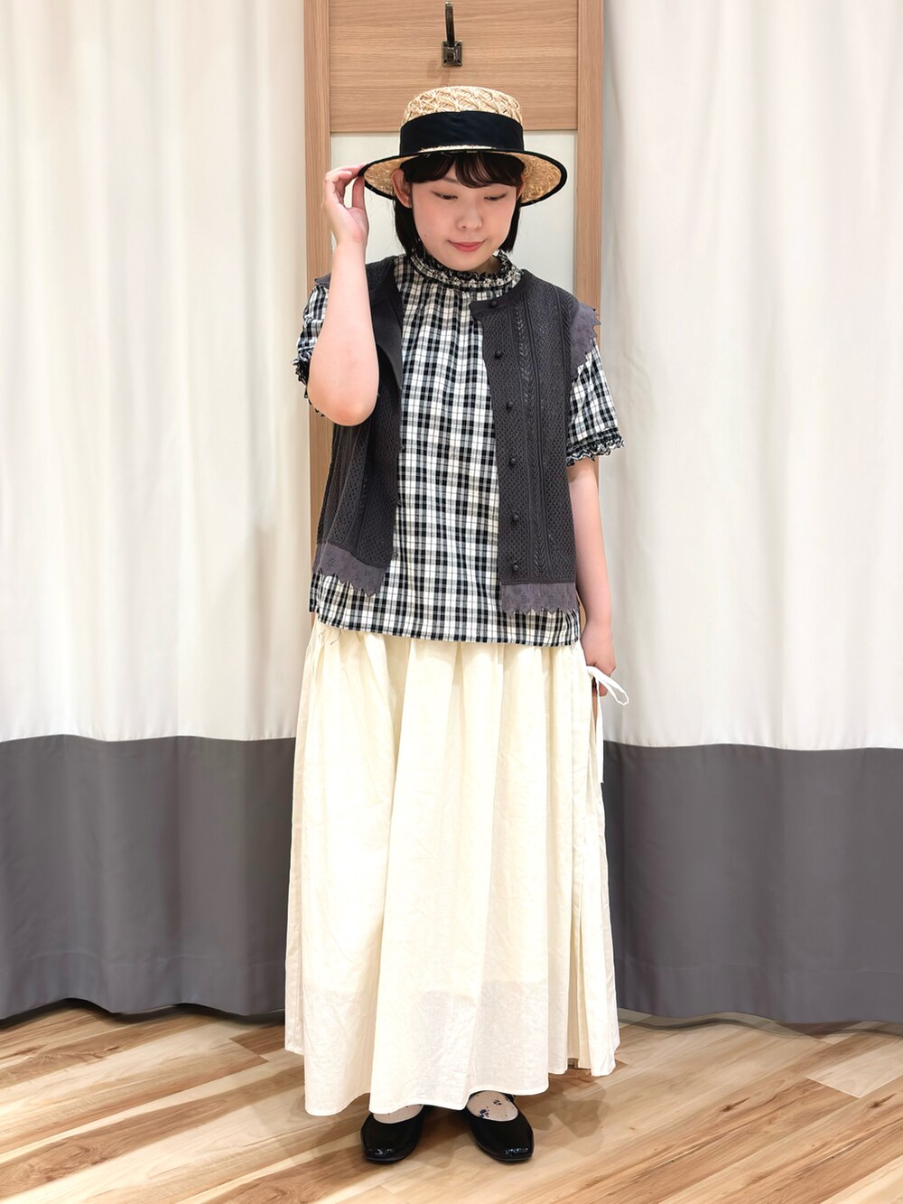 ブラック系のシャツ/ブラウス、グレー系のベスト、ホワイト系のスカートを着用したレディースの夏コーディネートの2枚目の写真