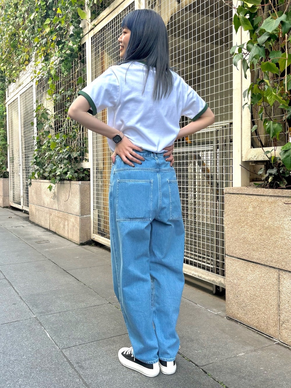 ブルー系のデニムパンツ、グリーン系のTシャツ/カットソー、ブラック系のスニーカーを着用したレディースの春コーディネートの4枚目の写真