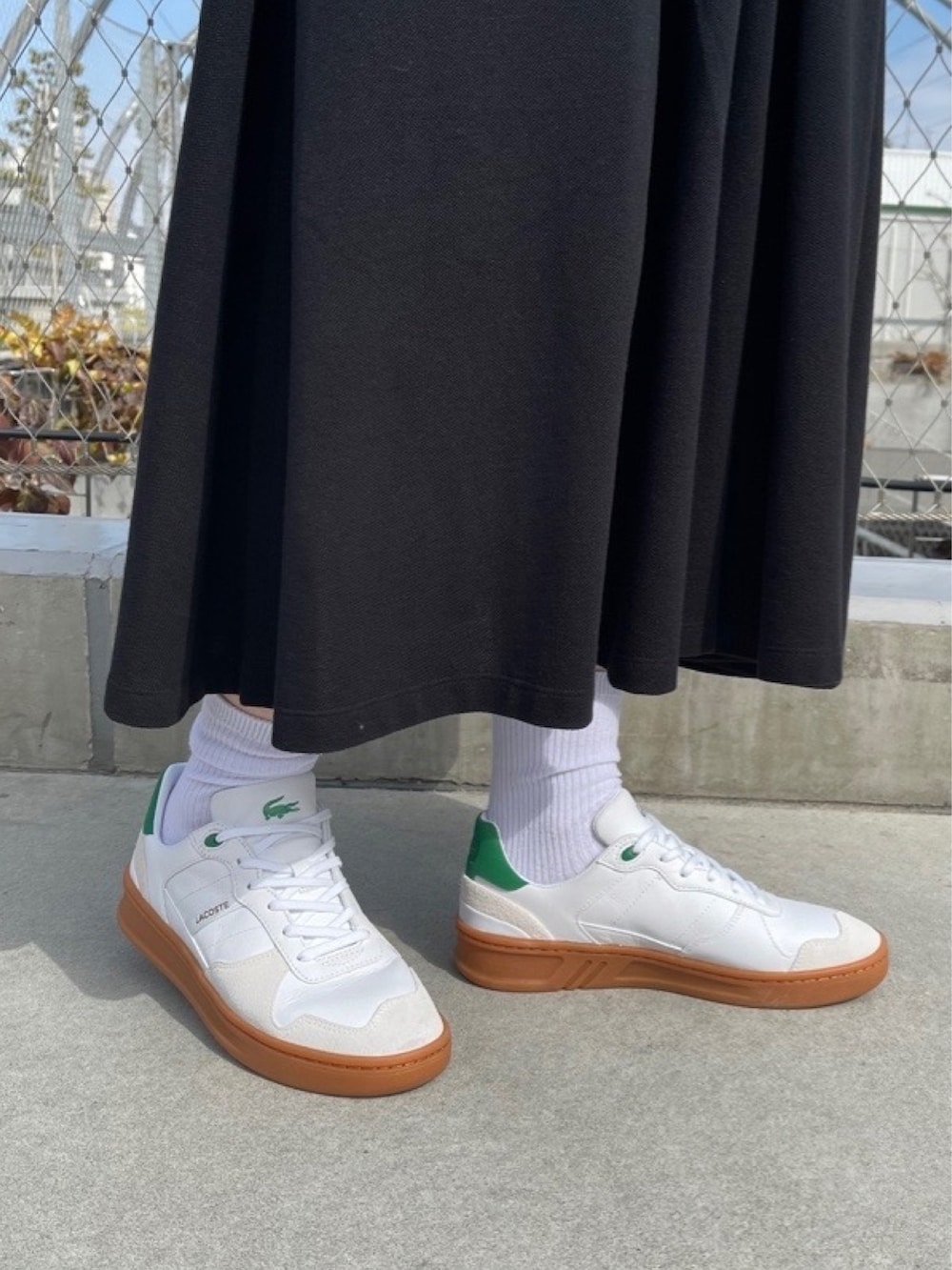 ブラック系のシャツワンピース、ホワイト系のスニーカー、ブラック系のバックパック/リュックを着用したレディースの春コーディネートの5枚目の写真