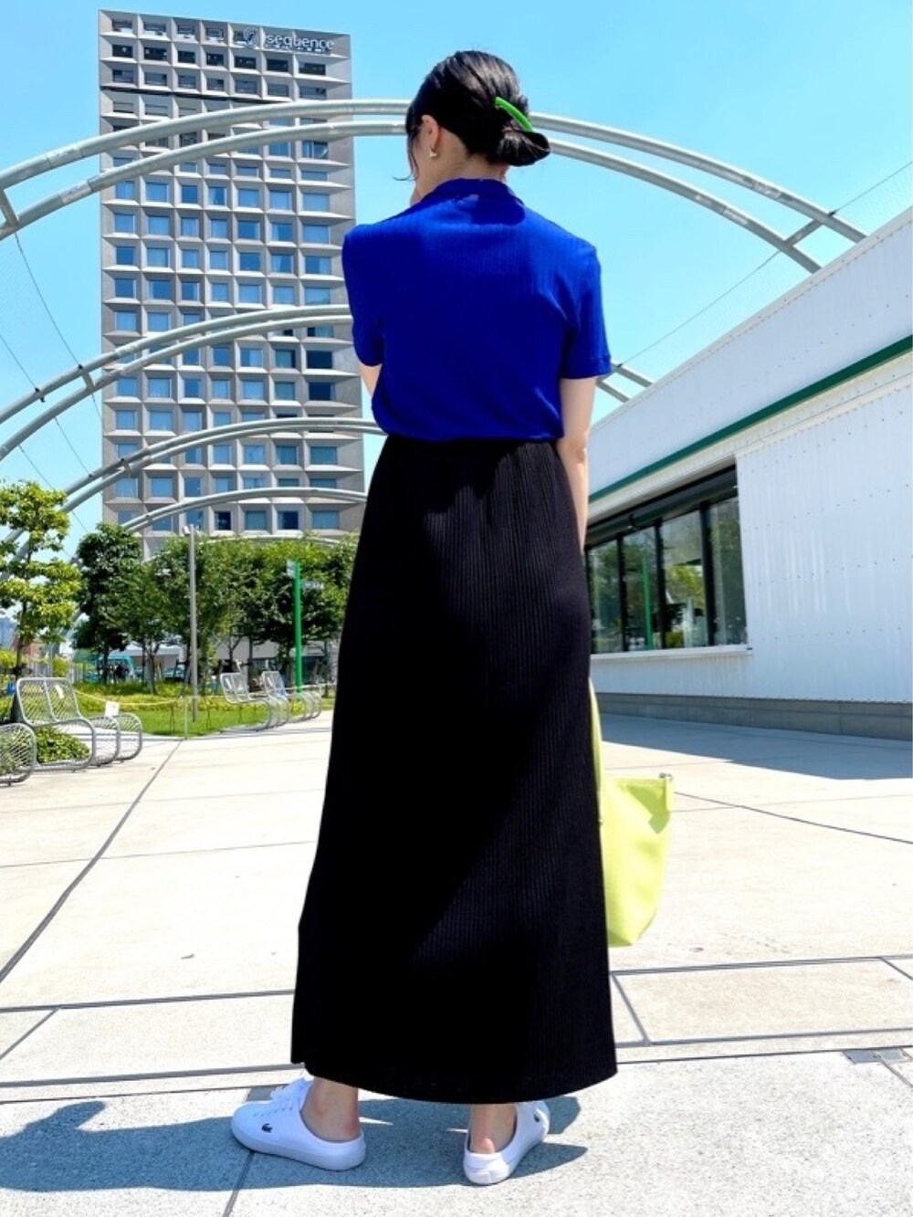 イエロー系のトートバッグ、ブルー系のポロシャツ、ホワイト系のスニーカーを着用したレディースの春コーディネートの3枚目の写真