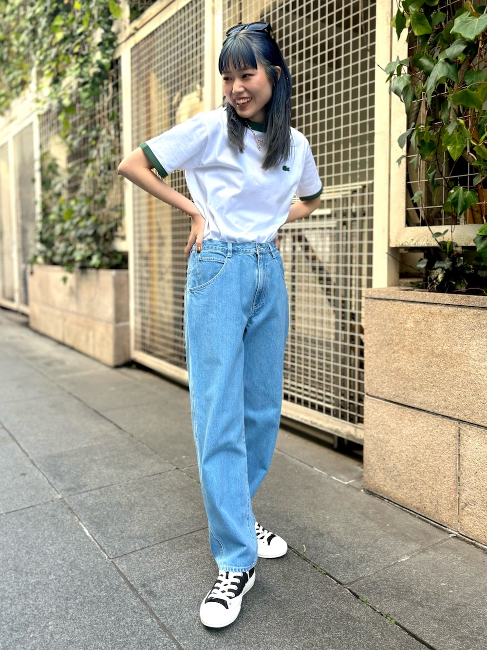ブルー系のデニムパンツ、グリーン系のTシャツ/カットソー、ブラック系のスニーカーを着用したレディースの春コーディネートの2枚目の写真