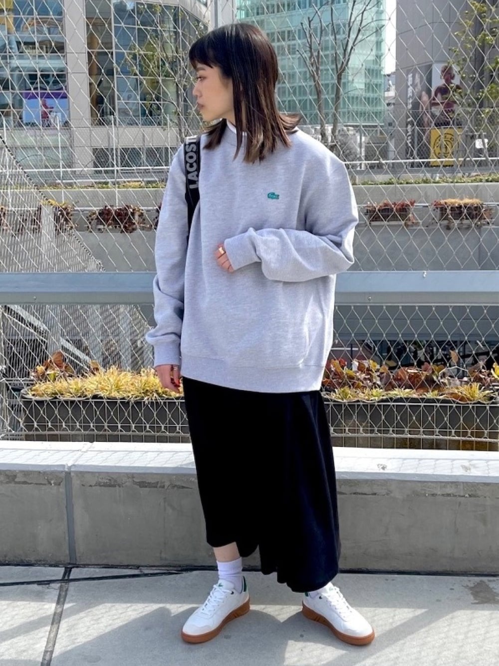 ブラック系のシャツワンピース、ホワイト系のスニーカー、ブラック系のバックパック/リュックを着用したレディースの春コーディネートの3枚目の写真