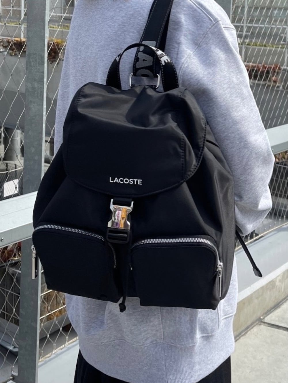 ブラック系のシャツワンピース、ホワイト系のスニーカー、ブラック系のバックパック/リュックを着用したレディースの春コーディネートの4枚目の写真