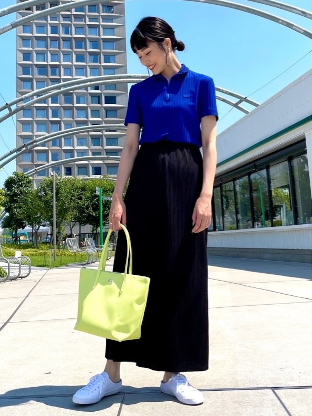 イエロー系のトートバッグ、ブルー系のポロシャツ、ホワイト系のスニーカーを着用したレディースの春コーディネートの2枚目の写真