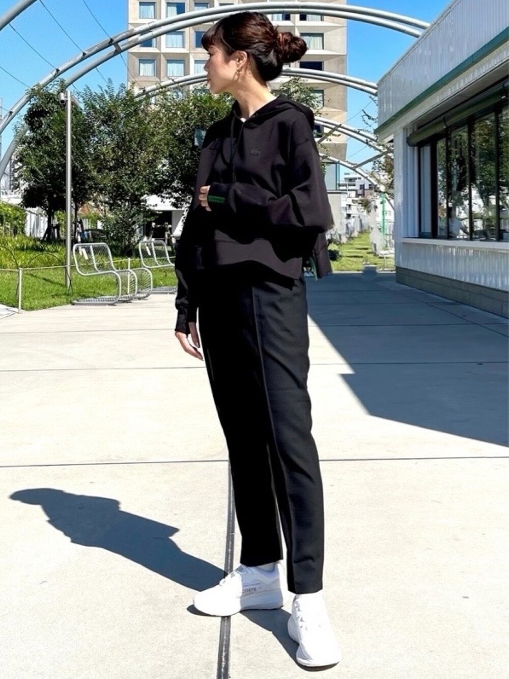 グリーン系のトレンチコート、オレンジ系のショルダーバッグ、ブラック系のパーカーを着用したレディースの春コーディネートの3枚目の写真