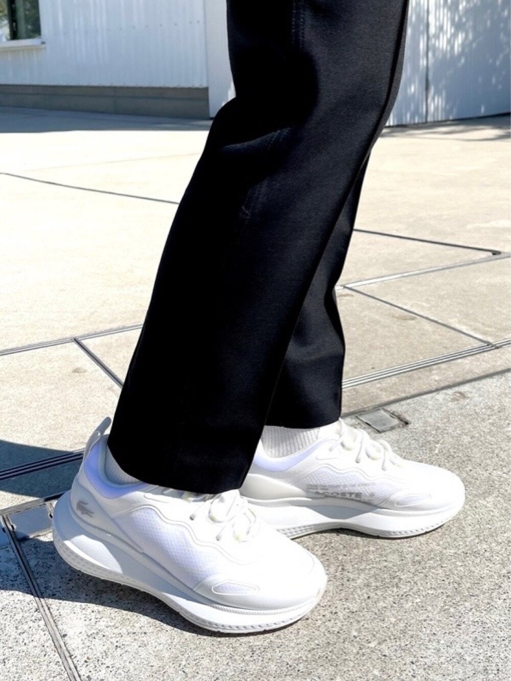 グリーン系のトレンチコート、オレンジ系のショルダーバッグ、ブラック系のパーカーを着用したレディースの春コーディネートの4枚目の写真