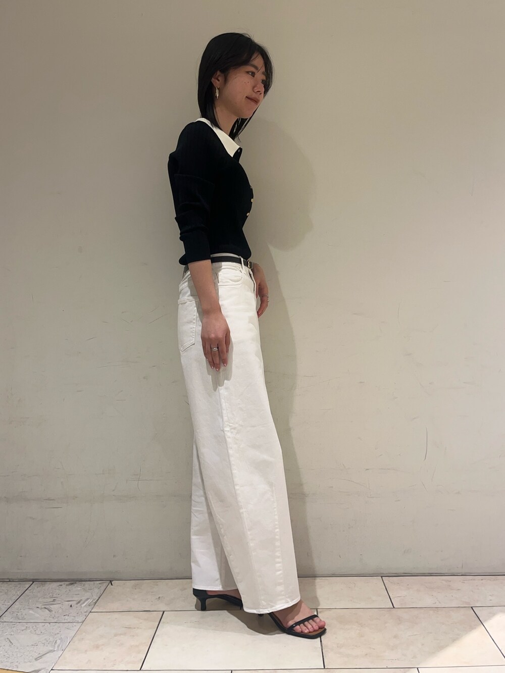 ブラック系のニット/セーター、ホワイト系のデニムパンツ、ブラック系のベルトを着用したレディースの冬コーディネートの3枚目の写真