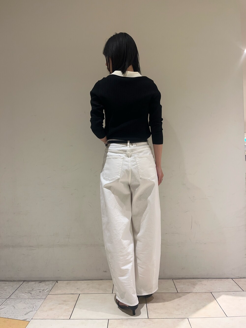 ブラック系のニット/セーター、ホワイト系のデニムパンツ、ブラック系のベルトを着用したレディースの冬コーディネートの4枚目の写真