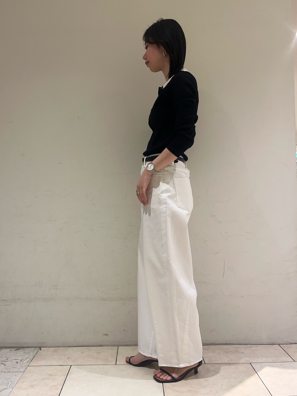 ブラック系のニット/セーター、ホワイト系のデニムパンツ、ブラック系のベルトを着用したレディースの冬コーディネートの5枚目の写真