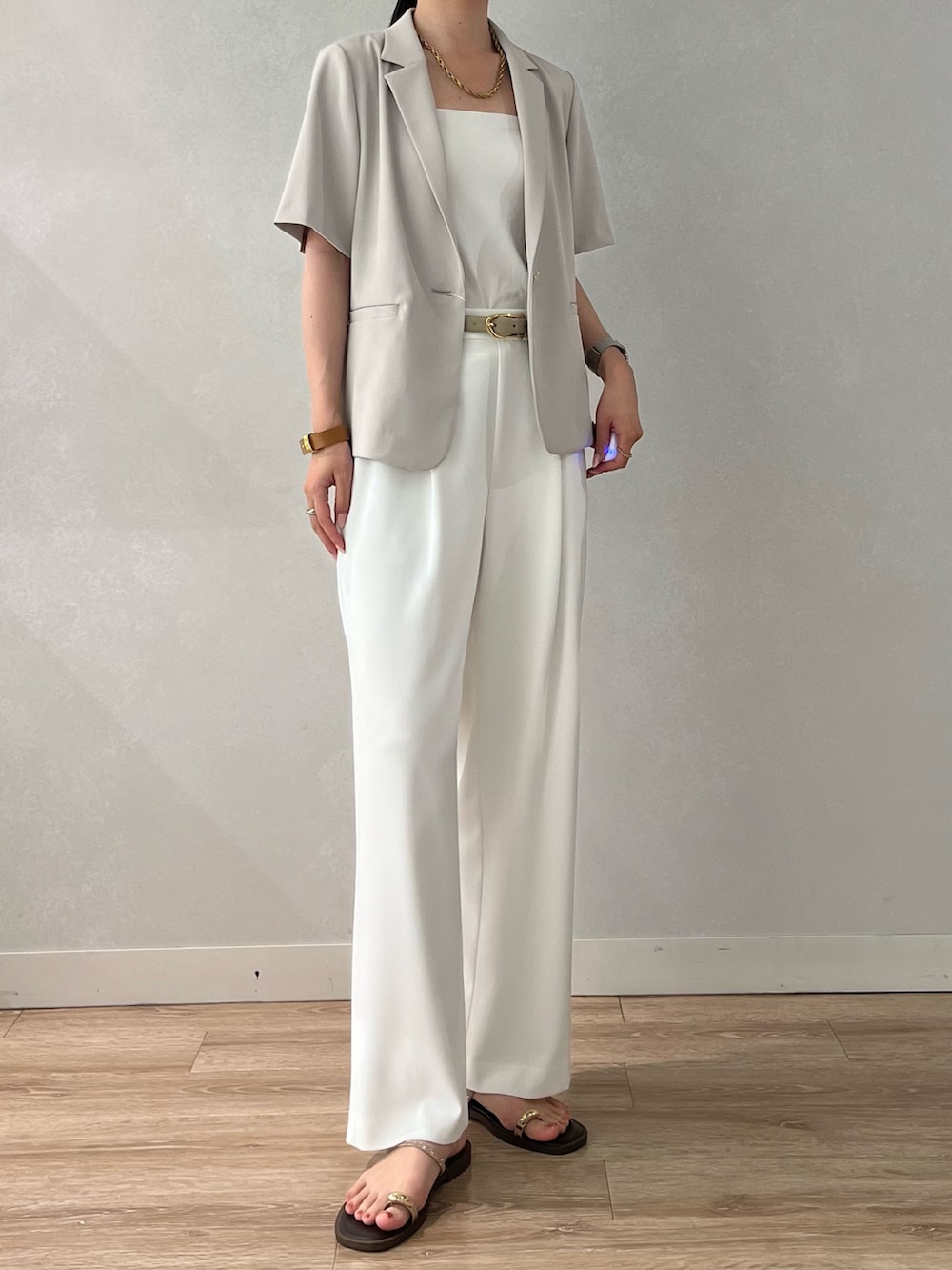 ベージュ系のテーラードジャケット、ホワイト系のその他パンツ、ブラウン系のサンダルを着用したレディースの夏コーディネートの2枚目の写真