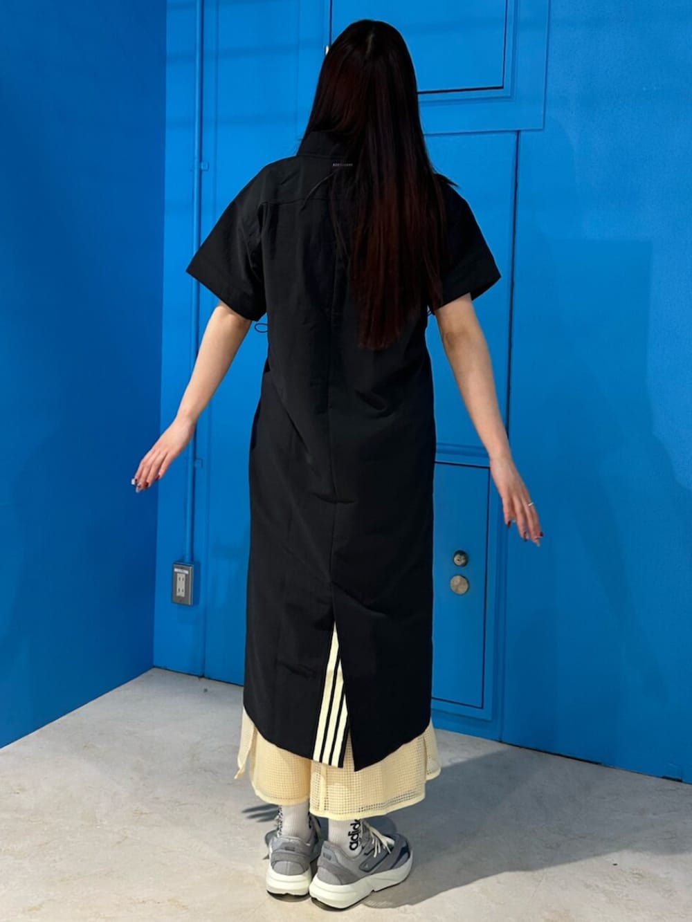 グレー系のスニーカー、ブラック系のワンピース、イエロー系のスカートを着用したレディースの春コーディネートの3枚目の写真