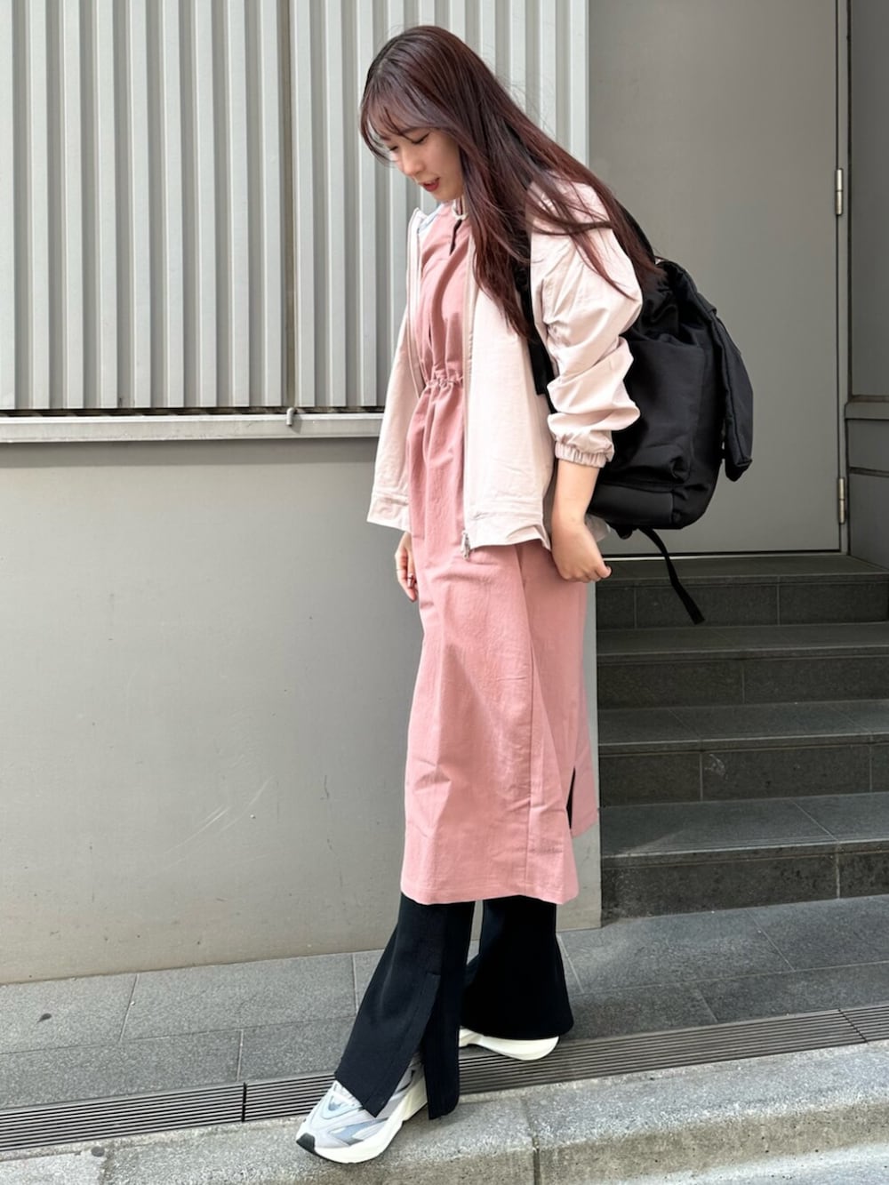 グレー系のスニーカー、ブラウン系のナイロンジャケット、ピンク系のワンピースを着用したレディースの春コーディネートの2枚目の写真