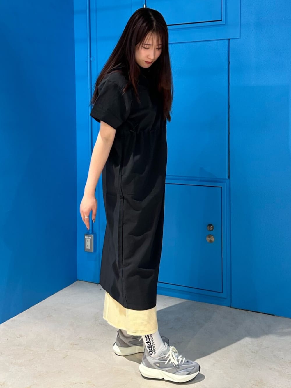 グレー系のスニーカー、ブラック系のワンピース、イエロー系のスカートを着用したレディースの春コーディネートの4枚目の写真