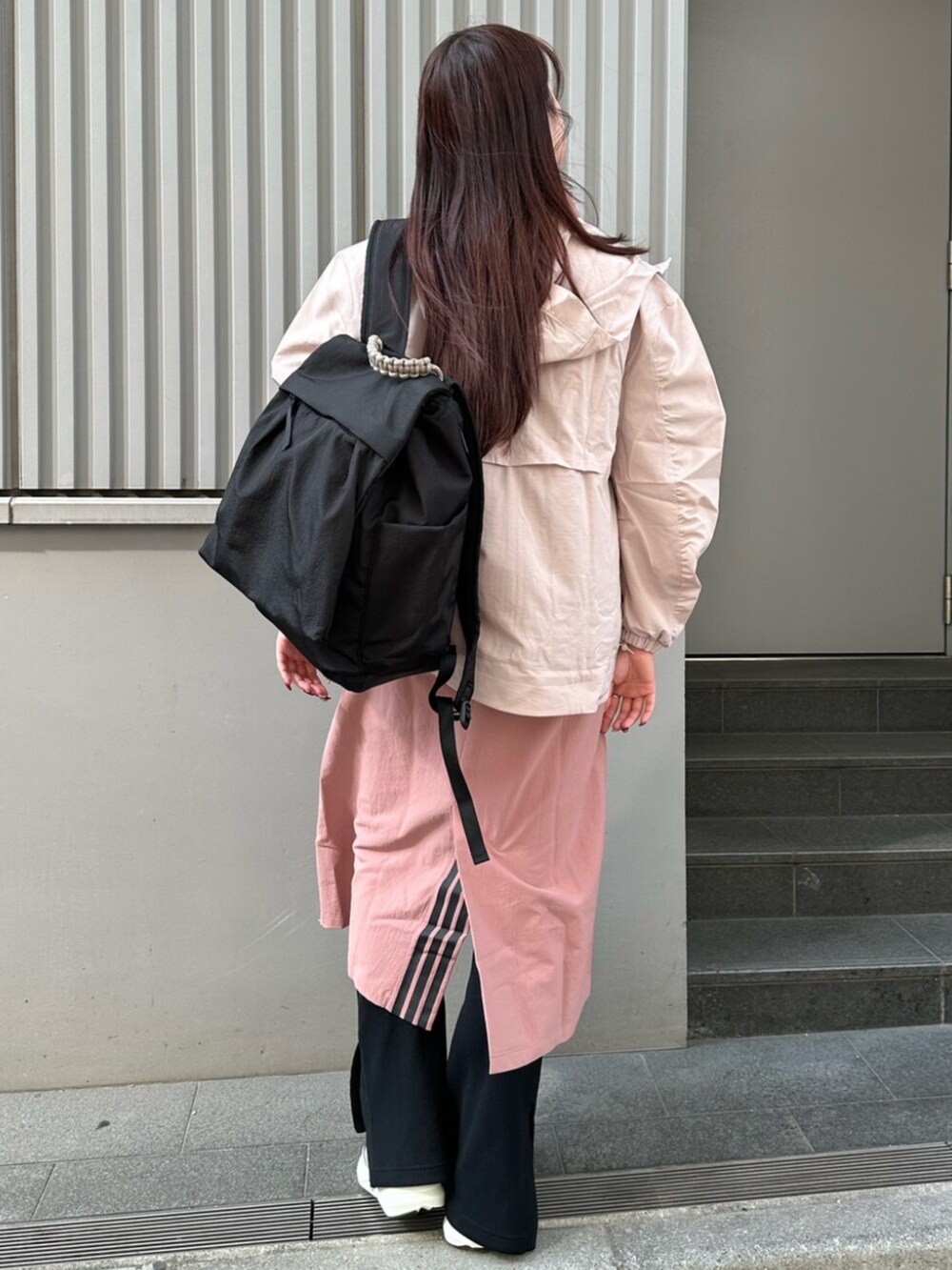 グレー系のスニーカー、ブラウン系のナイロンジャケット、ピンク系のワンピースを着用したレディースの春コーディネートの3枚目の写真