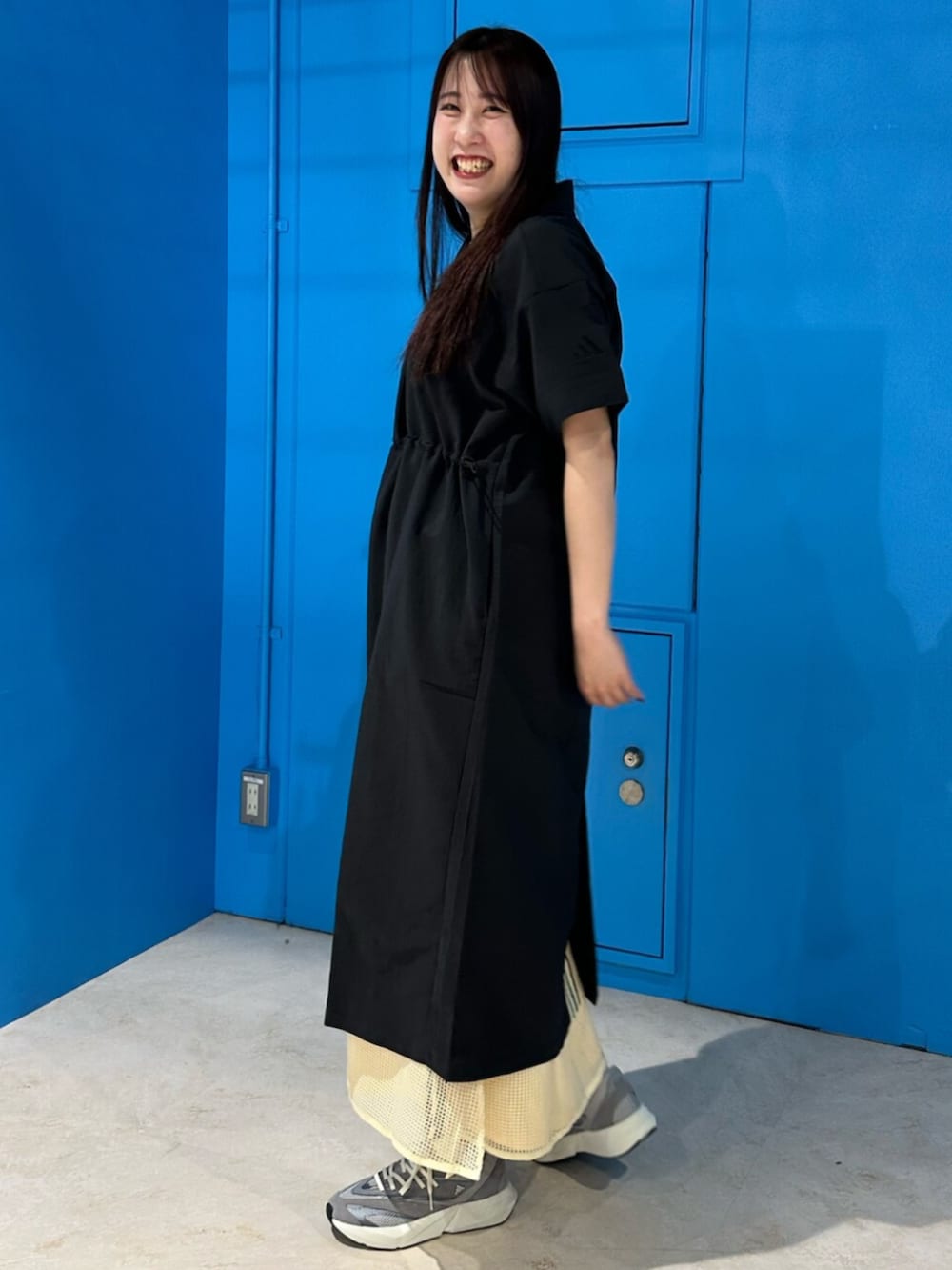 グレー系のスニーカー、ブラック系のワンピース、イエロー系のスカートを着用したレディースの春コーディネートの2枚目の写真