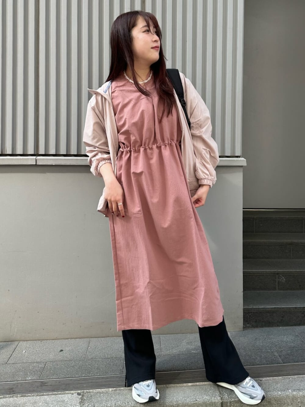 グレー系のスニーカー、ブラウン系のナイロンジャケット、ピンク系のワンピースを着用したレディースの春コーディネートの4枚目の写真