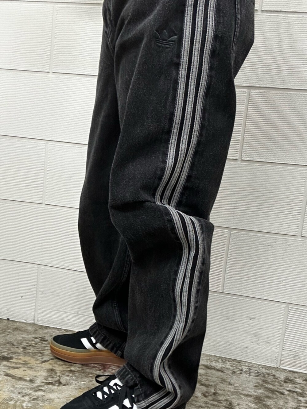 シルバー系のショルダーバッグ、ブラック系のデニムパンツ、ブルー系のジャージを着用したメンズの冬コーディネートの3枚目の写真