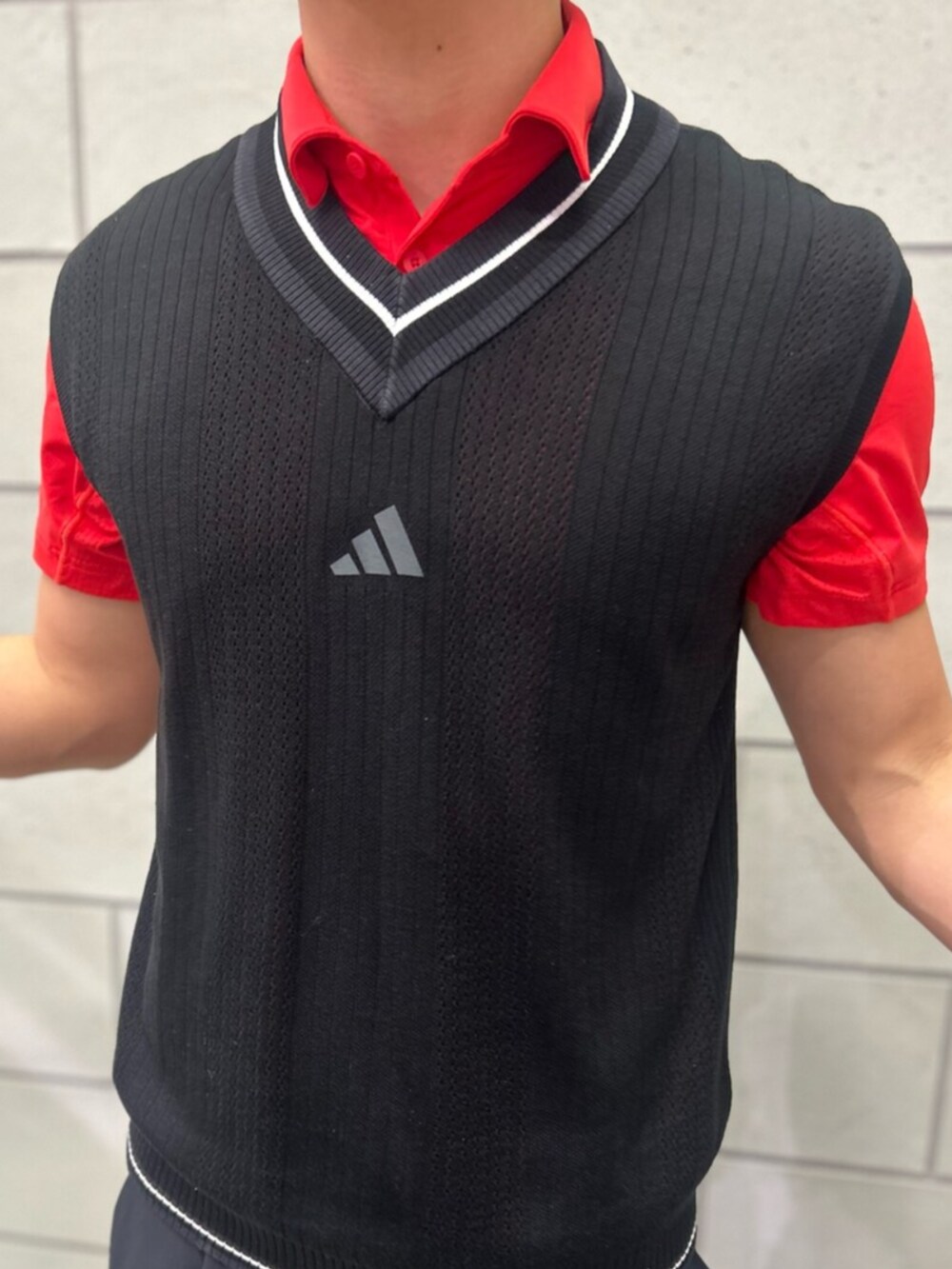 ブラック系のその他パンツ、ブラック系のベスト、レッド系のポロシャツを着用したメンズの春コーディネートの3枚目の写真