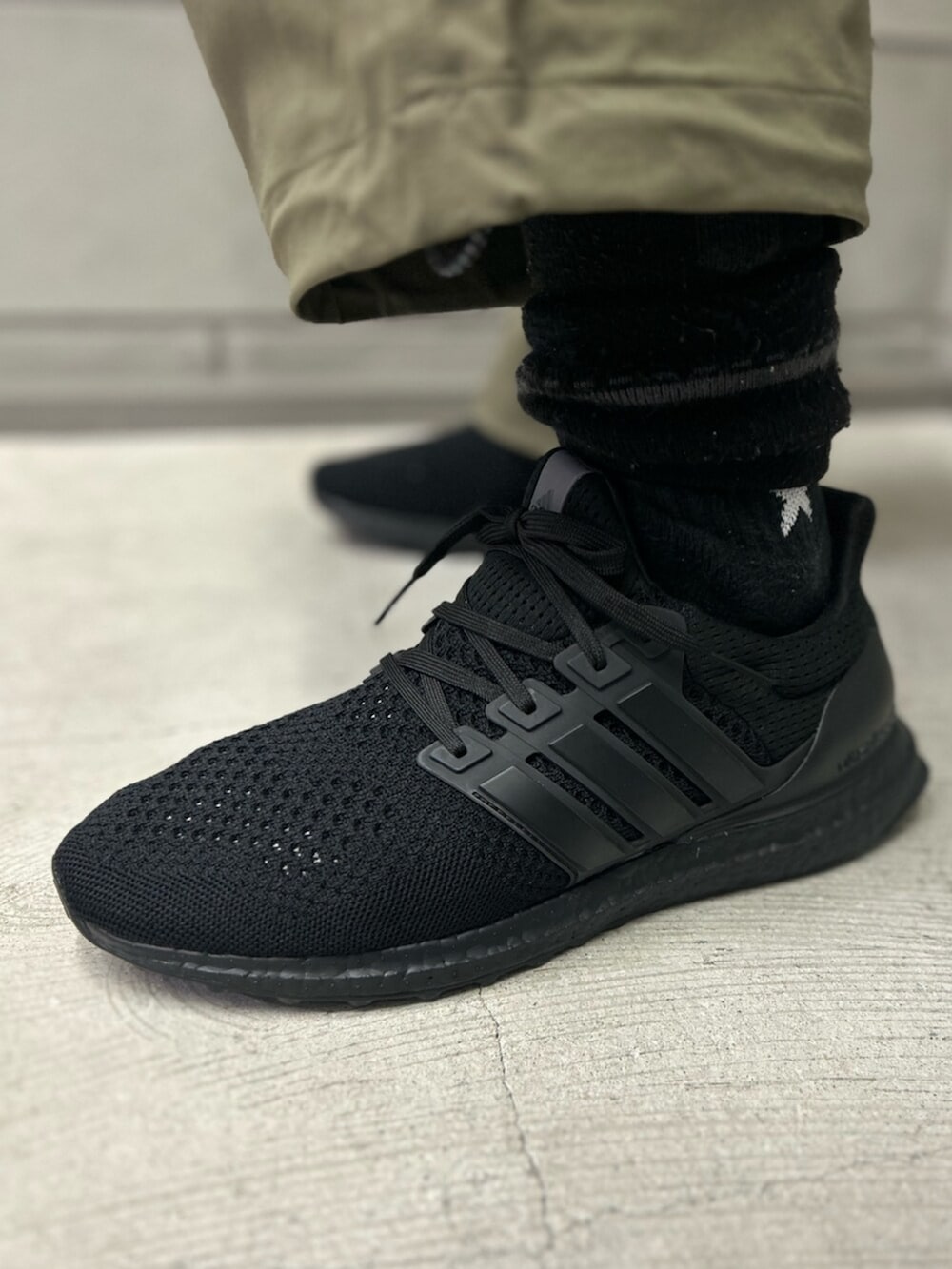 ブラック系のスニーカー、グリーン系のその他パンツ、ブラック系のキャップを着用したメンズの冬コーディネートの4枚目の写真