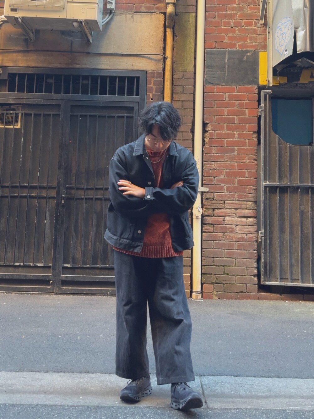 ブラック系のセットアップ、ブラック系のスニーカー、オレンジ系のニット/セーターを着用したメンズの春コーディネートの3枚目の写真