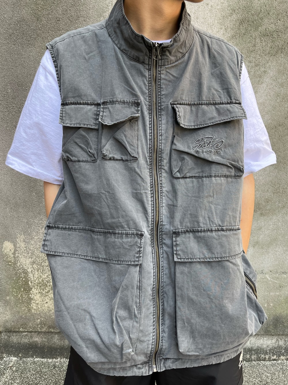 グレー系のベスト、ブラック系のカーゴパンツ、ブラック系のモカシン/デッキシューズを着用したメンズの夏コーディネートの3枚目の写真
