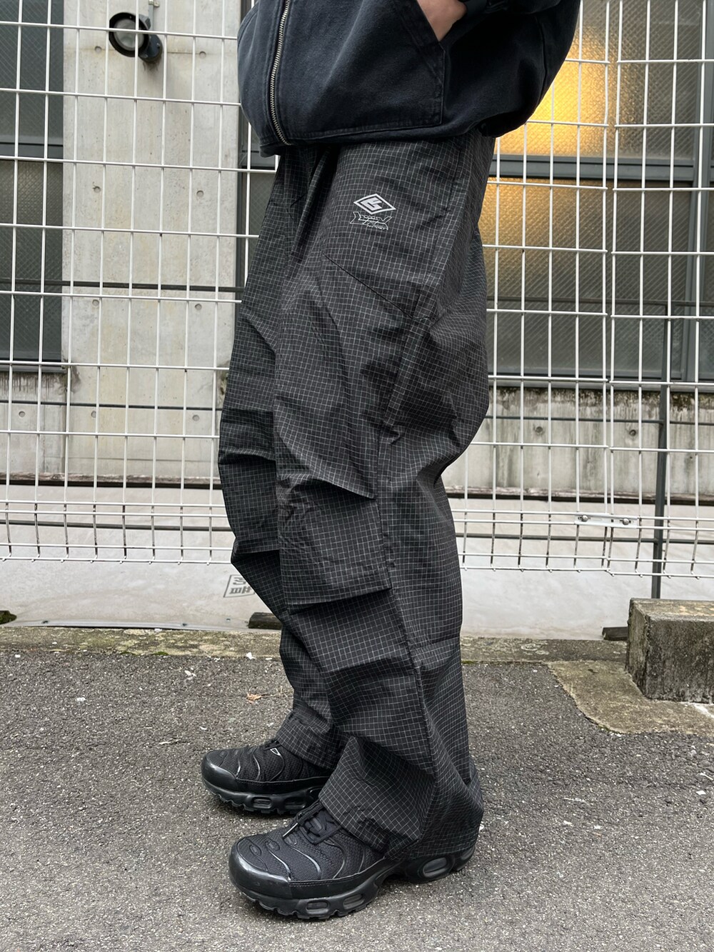 ブラック系のブルゾン、ブラック系のカーゴパンツ、ブラック系のスニーカーを着用したメンズの春コーディネートの3枚目の写真