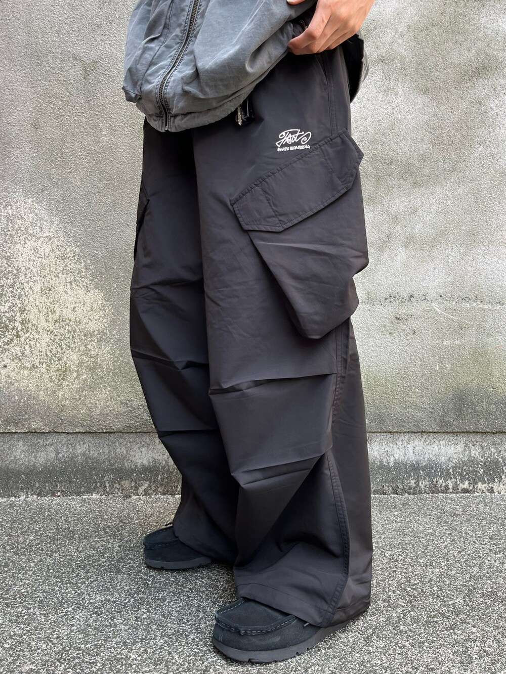 グレー系のベスト、ブラック系のカーゴパンツ、ブラック系のモカシン/デッキシューズを着用したメンズの夏コーディネートの5枚目の写真