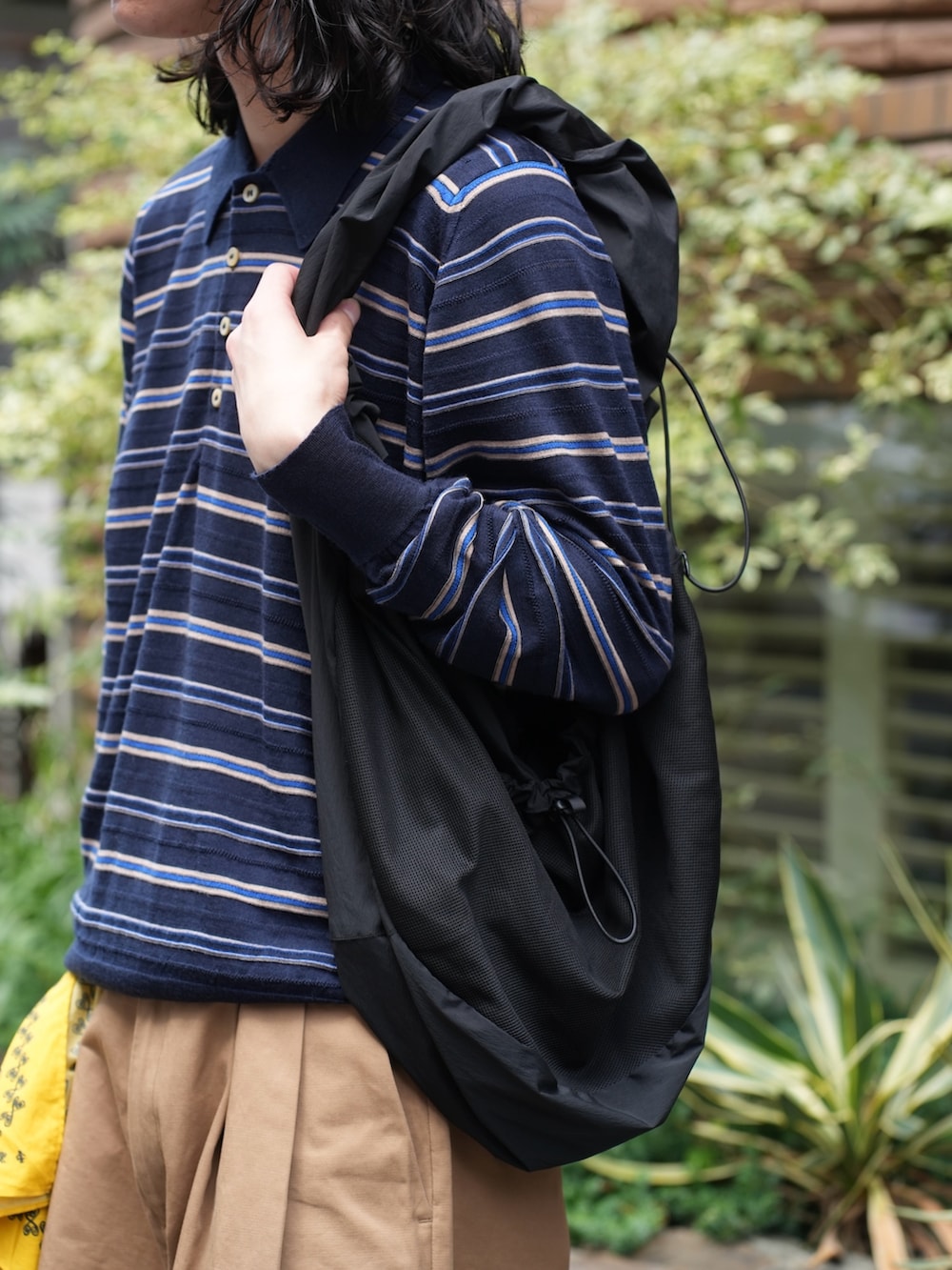 ブラック系のトートバッグ、イエロー系のその他パンツ、レッド系のスニーカーを着用したメンズの夏コーディネートの2枚目の写真