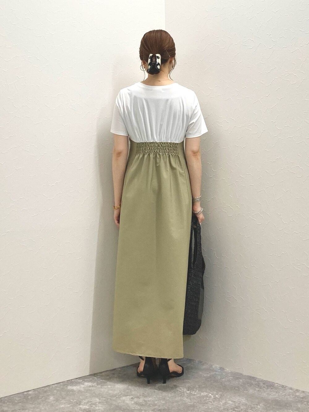 グリーン系のワンピース、ブラック系のサンダル、ブラック系のかごバッグを着用したレディースの春コーディネートの5枚目の写真