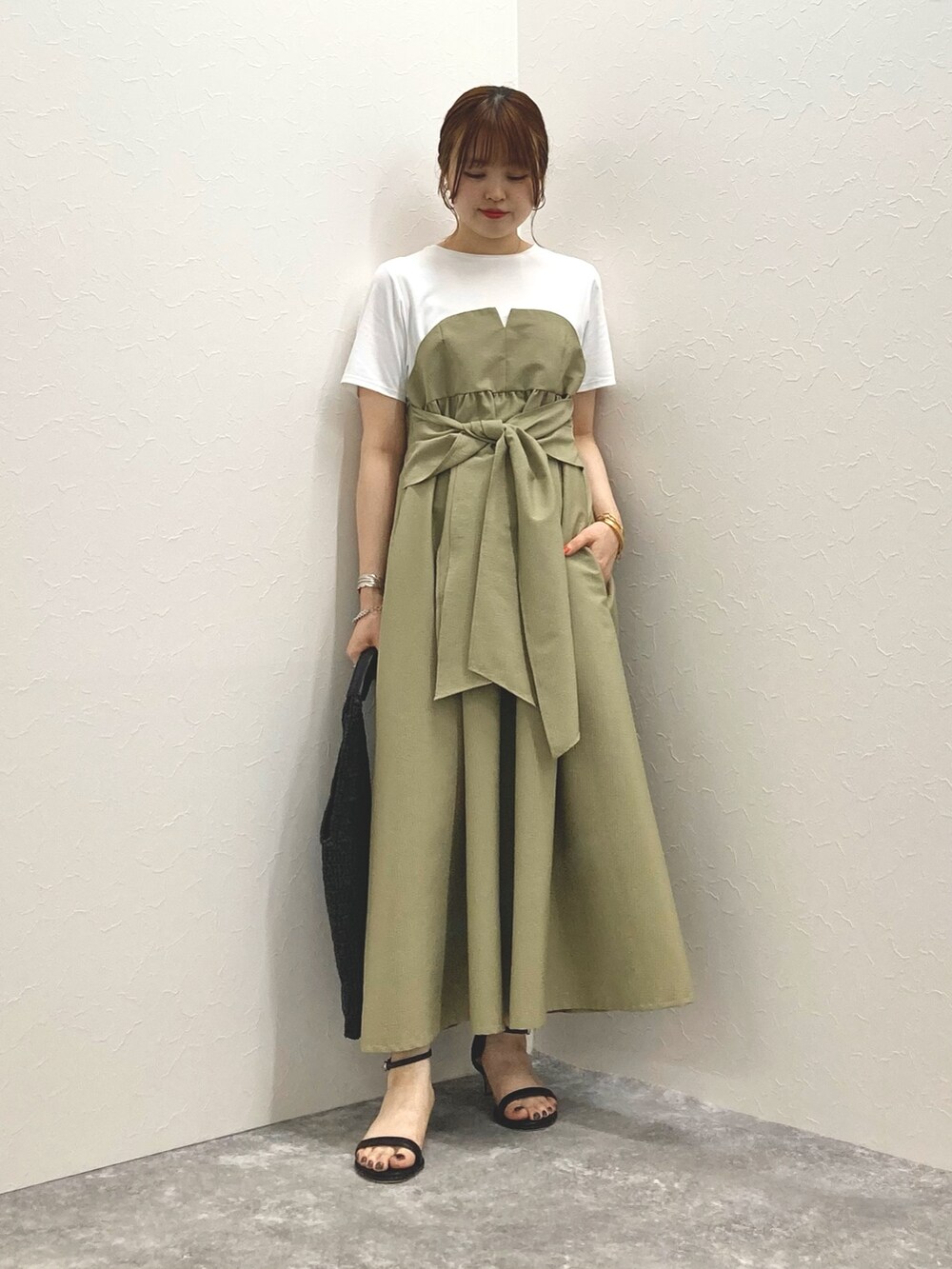 グリーン系のワンピース、ブラック系のサンダル、ブラック系のかごバッグを着用したレディースの春コーディネートの6枚目の写真