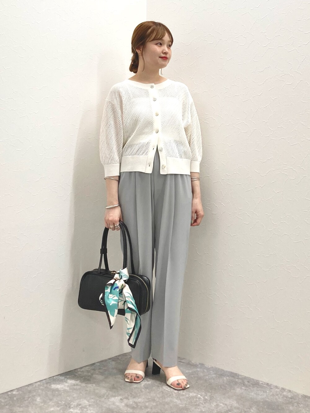 ホワイト系のカーディガン/ボレロ、グレー系のその他パンツ、ブラック系のボストンバッグを着用したレディースの春コーディネートの8枚目の写真