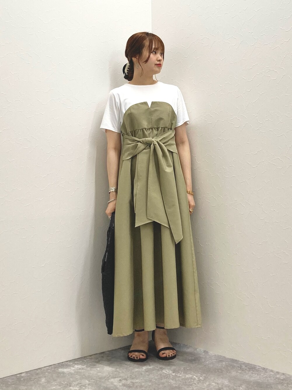 グリーン系のワンピース、ブラック系のサンダル、ブラック系のかごバッグを着用したレディースの春コーディネートの3枚目の写真