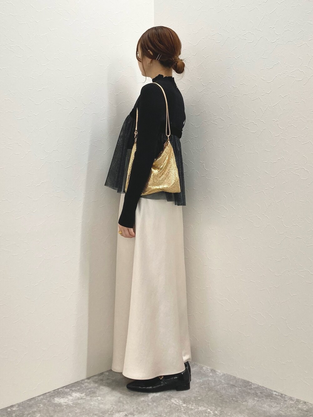 ホワイト系のニット/セーター、ブラック系のシャツ/ブラウス、ゴールド系のクラッチバッグを着用したレディースの秋コーディネートの3枚目の写真
