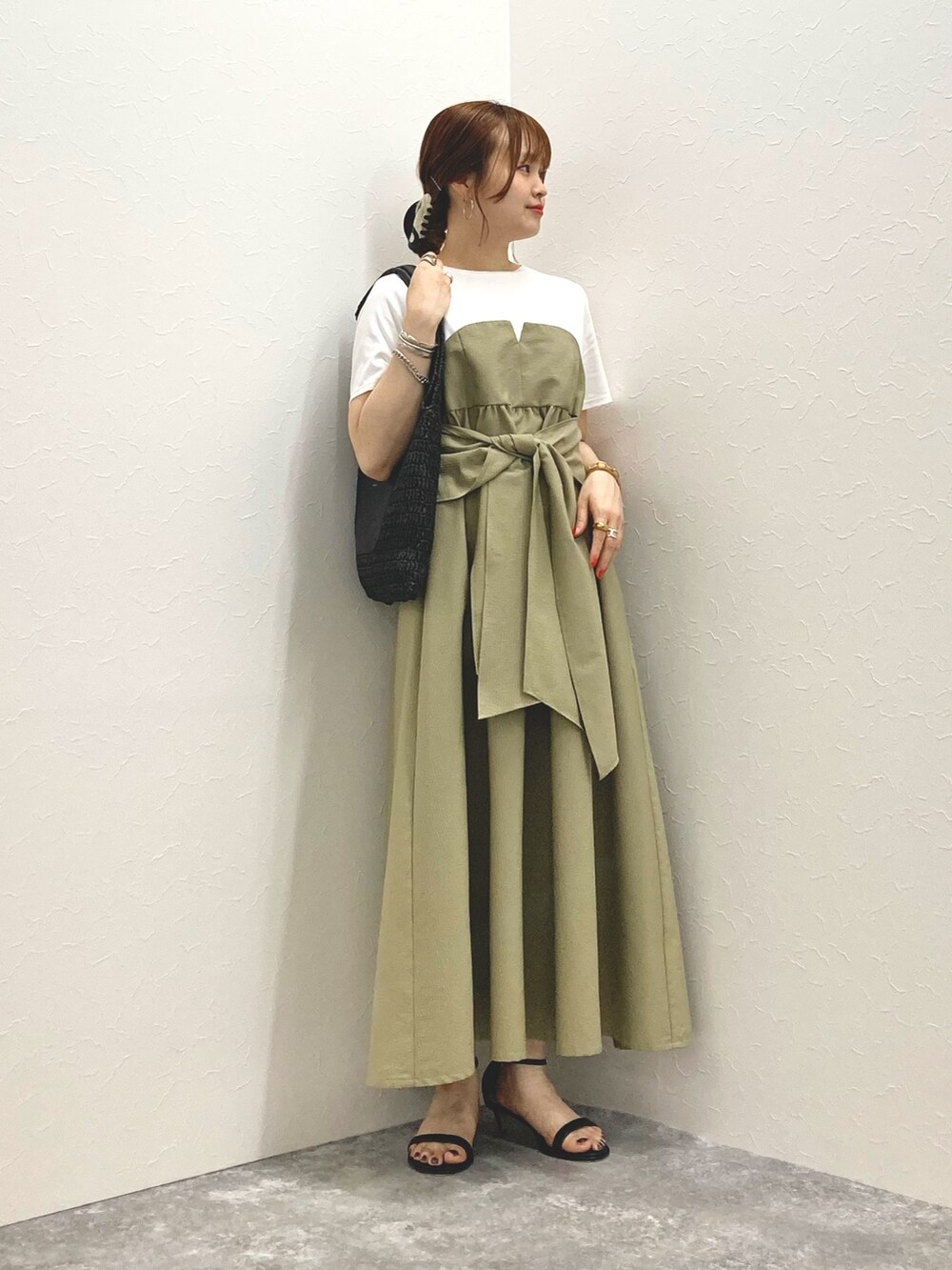 グリーン系のワンピース、ブラック系のサンダル、ブラック系のかごバッグを着用したレディースの春コーディネートの2枚目の写真