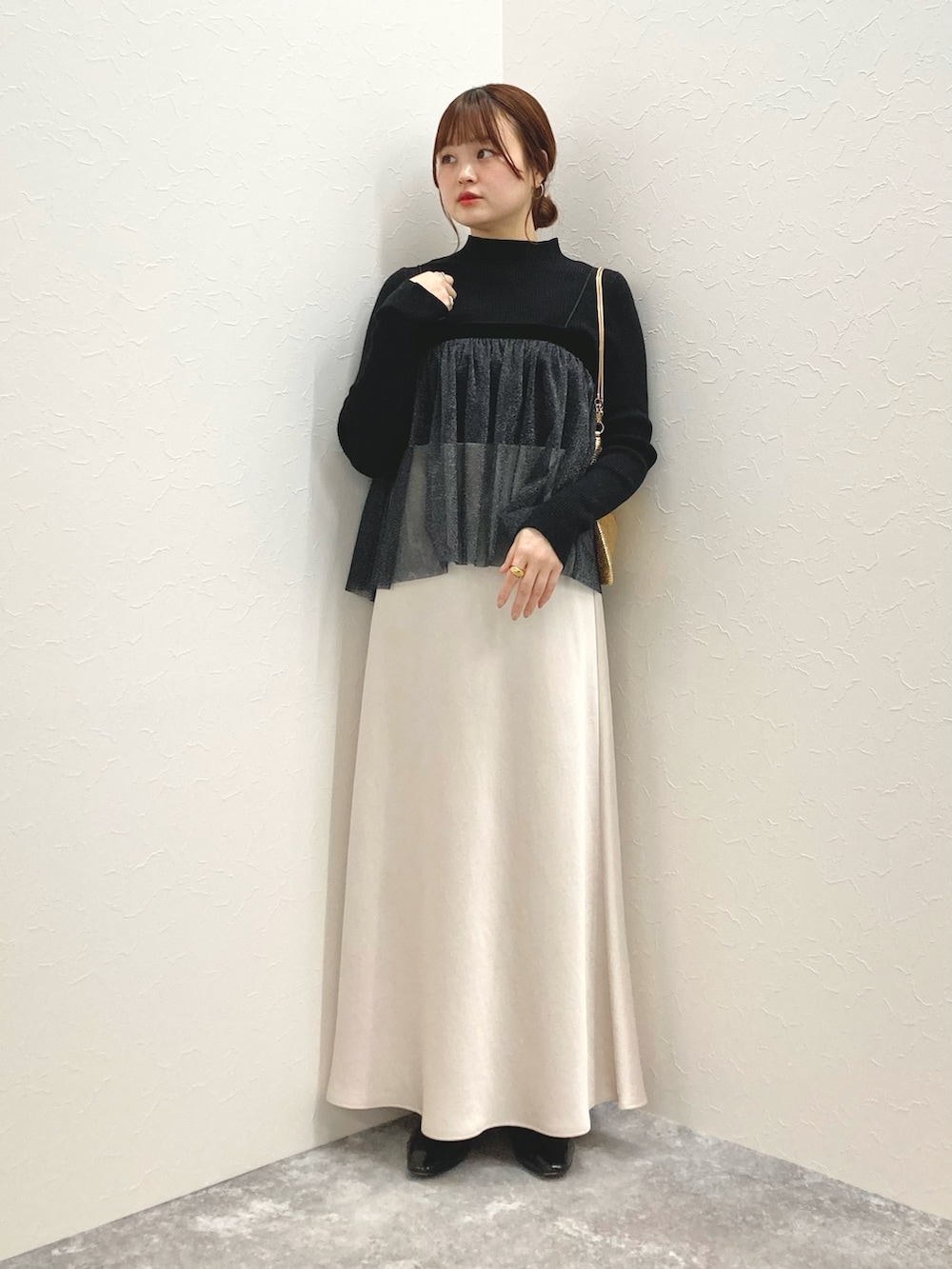 ホワイト系のニット/セーター、ブラック系のシャツ/ブラウス、ゴールド系のクラッチバッグを着用したレディースの秋コーディネートの6枚目の写真